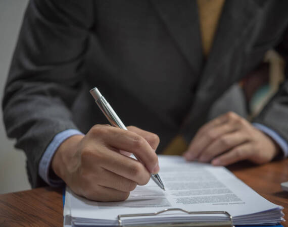 businessman signs documents with a pen making the signature on desk.